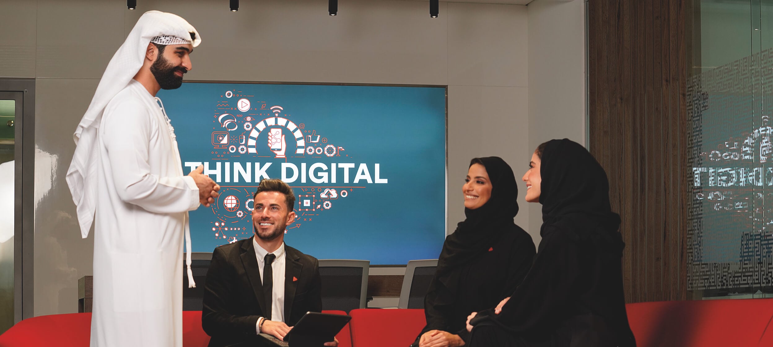 Three people sitting while being greeted by a man, with the words Think Digital displayed in the background.